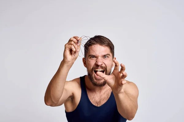 Hombre con un masajeador para la cabeza y en una camiseta azul sobre un fondo claro relajante barba emociones — Foto de Stock