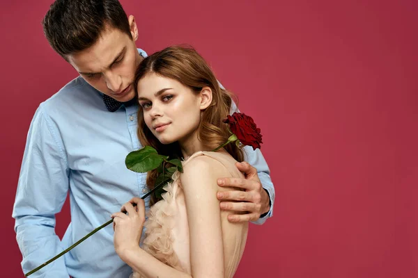 Milenci lidé s růží v rukou na růžové izolované pozadí objetí emoce štěstí romantika pocity — Stock fotografie