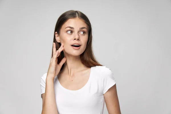 Uma mulher com uma expressão surpresa olha para uma camiseta branca — Fotografia de Stock