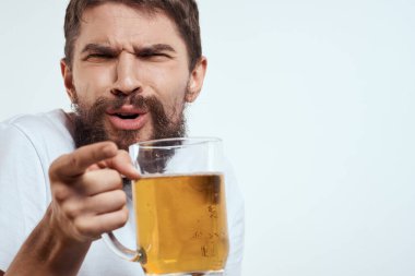 Elinde bir kupa bira ve beyaz tişörtlü açık renk bıyıklı sakallı bir adam.