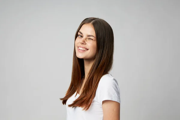 흰색 티셔츠를 입고 밝은 배경에서 윙크하는 행복 한 여성 — 스톡 사진