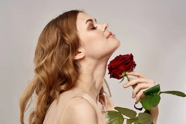 Donna dai capelli rossi con una rosa tra le mani su uno sfondo chiaro emozioni modello ritratto primo piano — Foto Stock