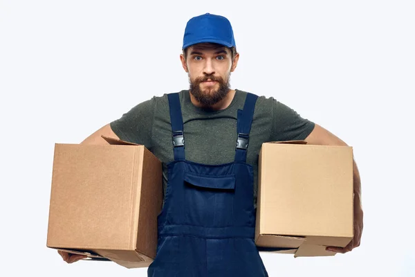 Ein Mann in Arbeitsuniform mit einer Schachtel in der Hand liefert Transportarbeiten aus — Stockfoto