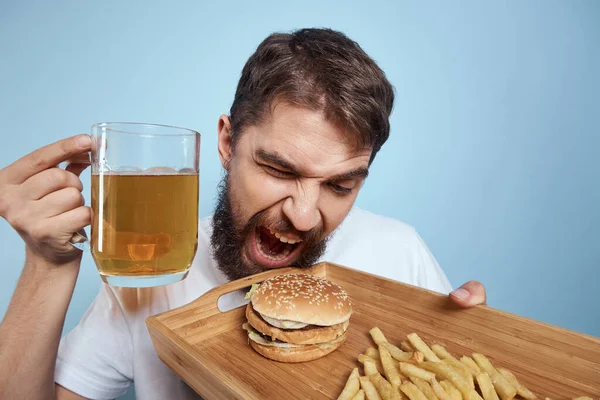 Gai homme bière tasse hamburger frites fast food régime bleu fond close-up — Photo