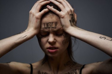 Vücudunda çirkin yazılar olan bir kadın elleriyle kendine dokunuyor gerginlik hüsranı nefreti