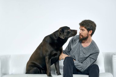 Kanepede evcil köpeği olan bir adam. Arkadaşlarıyla eğleniyor.