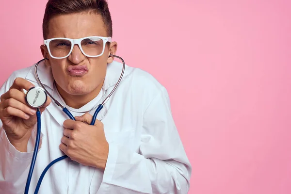 Νεαρός γιατρός με στηθοσκόπιο και γυαλιά σε ροζ φόντο νοσοκόμα οικότροφος μοντέλο — Φωτογραφία Αρχείου