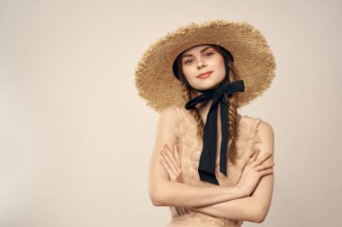 Bej elbiseli, hasır şapkalı, siyah kurdele takmış, manken görünümlü romantik bir kız.