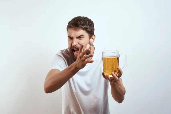 Homem com uma caneca de cerveja em suas mãos e um branco t-shirt luz fundo bigode barba emoções modelo — Fotografia de Stock