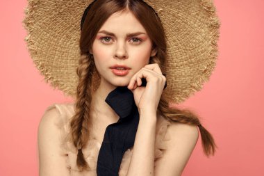 Hasır şapkalı bir kızın portresi pembe arka plan duyguları yakın plan güzel yüz modeli örgüler.