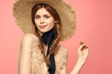 Hasır şapkalı bir kızın portresi pembe arka plan duyguları yakın plan güzel yüz modeli örgüler.