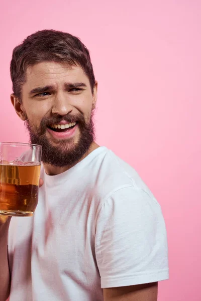 Γενειοφόρος με μια κούπα μπύρα σε ροζ φόντο διασκεδαστικά συναισθήματα θέα ενός λευκού T-shirt μεθυσμένος — Φωτογραφία Αρχείου