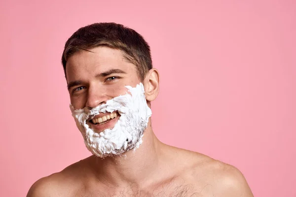 Homem com navalha e espuma branca em seu rosto rosa fundo nu torso tratamentos de banho — Fotografia de Stock