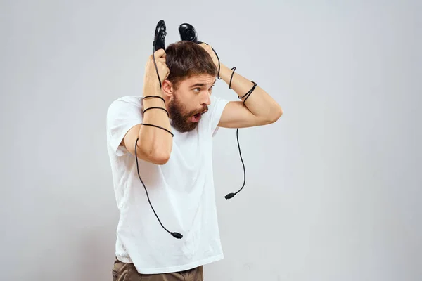 Een man houdt in zijn handen twee joysticks spelen vrijetijdsbesteding technologie levensstijl wit t-shirt — Stockfoto