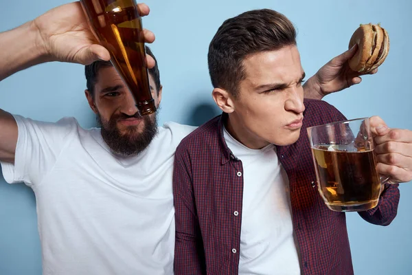 Deux amis ivres joyeux buvant de la bière mode de vie émotions sur un fond bleu — Photo