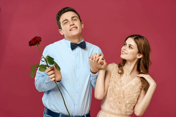 Enamored man and woman with a red flower on a pink background hug each other Copy Space — Stock Photo, Image