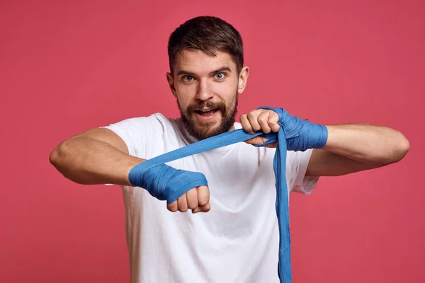 Uomo in t-shirt bianca si lega la mano con una benda arti marziali sfondo rosa — Foto Stock