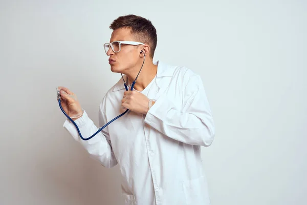 Lekarz w sukni medycznej ze stetoskopem i okularami na jasnym tle przycięty widok portret — Zdjęcie stockowe