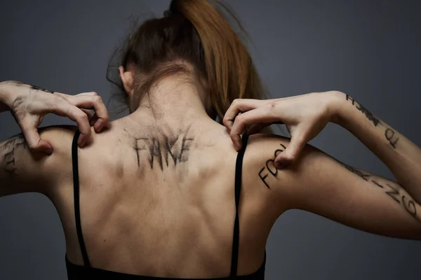 Женщина с оскорбительными надписями на теле трогает себя руками стресс разочарование ненависть — стоковое фото