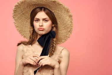 Hasır şapkalı bir kızın portresi pembe arka plan duyguları yakın plan güzel yüz modeli örgüler.