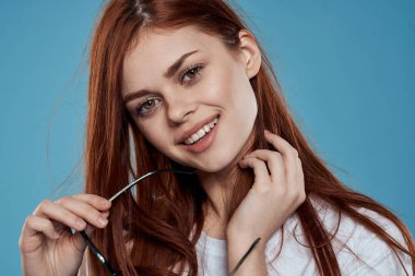 Ellerinde güneş gözlüğü olan güzel bir kadın yaşam tarzı duyguları uzun saç makyaj malzemesi arka planda beyaz tişört.