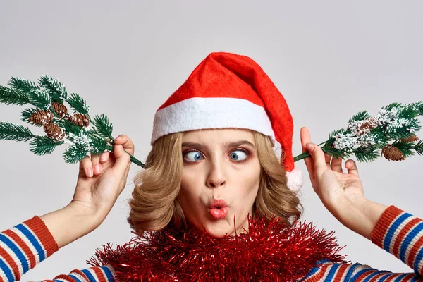 Kvinna med julgran grenar och i en röd hatt på en ljus bakgrund nyår — Stockfoto