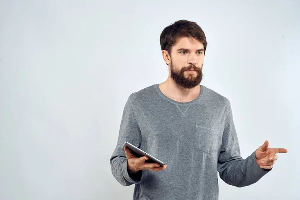 Ein Mann in einem grauen Pullover ein Tablet in den Händen von Emotionen Internet-Technologie Lifestyle Licht Hintergrund — Stockfoto