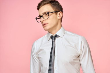 Beyaz gömlekli, kravatlı, gözlüklü, kendine güvenen, resmi pembe arka planlı bir iş adamı.