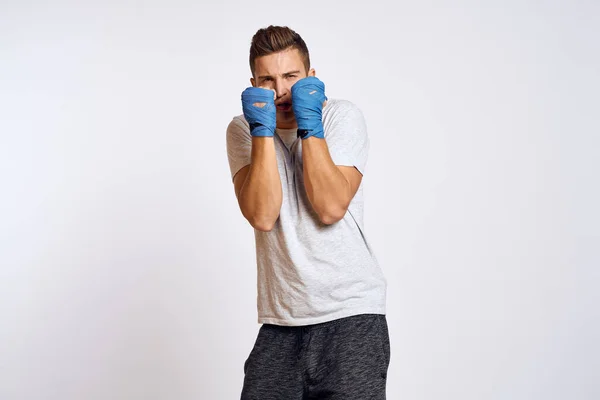 Boxer maschile sportivo in guanti blu che praticano pugni su uno sfondo leggero vista ritagliata — Foto Stock
