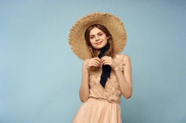 Mavi arka planda pembe elbiseli bir kız elleriyle romantik modeller yapıyor.