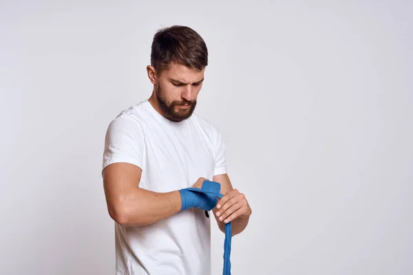 Homem de esportes em branco t-shirt azul bandagens de boxe em seus exercícios de treino de braços — Fotografia de Stock