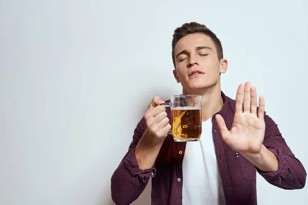 Bêbado homem com uma caneca de cerveja férias álcool estilo de vida em uma camisa vermelha emoções luz fundo — Fotografia de Stock