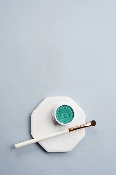 Sombra de olhos verde e pincel de maquiagem no fundo isolado do suporte branco — Fotografia de Stock