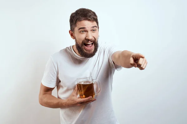 Homme avec une tasse de bière dans ses mains et un t-shirt blanc fond clair moustache barbe émotions modèle — Photo