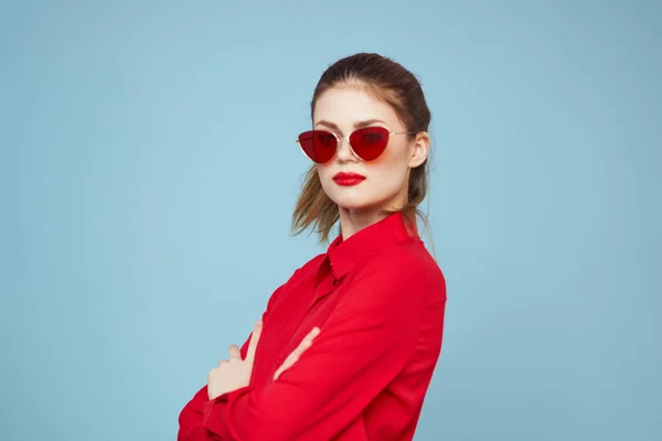 Koyu renk gözlüklü, kırmızı dudaklı, cazibeli stüdyo mavi arka planlı bir kadın. — Stok fotoğraf