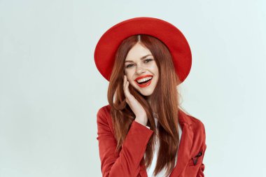 Kırmızı şapkalı güzel bir kadın. Ceket, şık makyaj, hafif arka plan stüdyosu.