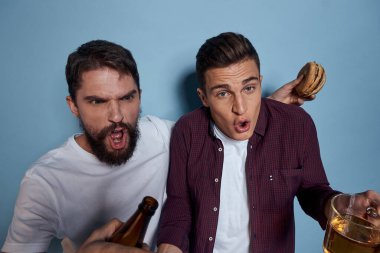 İki neşeli sarhoş arkadaş mavi bir arka planda bira içiyorlar.