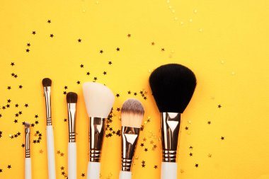 Sarı arka plan kırpılmış görünümde farklı boyutlarda makyaj fırçaları Boşluğu Kopyala