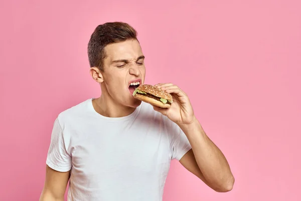 Muž s velkým hamburger na růžovém pozadí kalorie rychlé občerstvení oříznutý pohled kopírovat prostor close-up — Stock fotografie