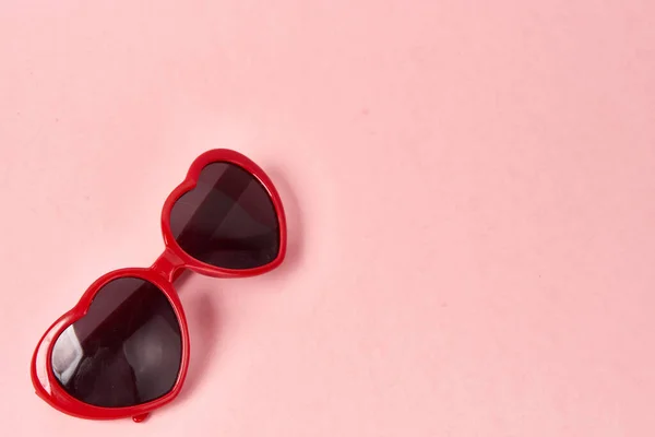 गुलाबी पृष्ठभूमि पर लाल फ्रेम के साथ दिल के आकार का धूप का चश्मा — स्टॉक फ़ोटो, इमेज