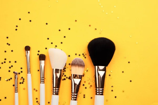 Pinceles de maquillaje de diferentes tamaños sobre fondo amarillo recortado vista Copiar espacio —  Fotos de Stock