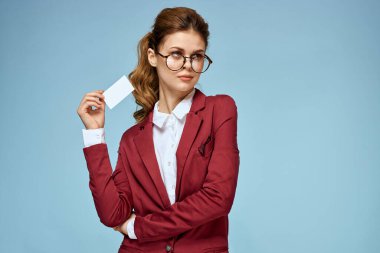 İş kadını kırmızı ceketli, gözlüklü, yönetici mavi arka planlı.