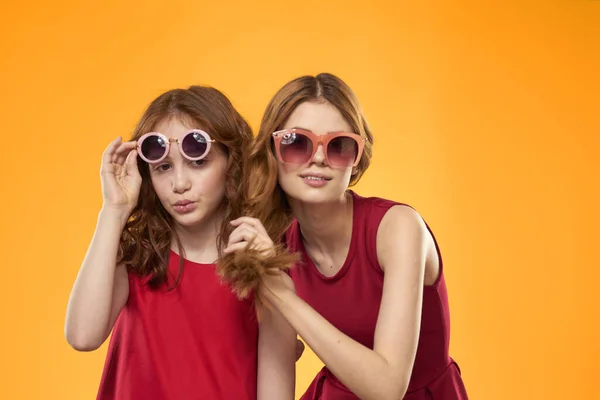 Hermanas felices en vestidos rojos sobre un fondo amarillo se están divirtiendo y gesticulando Copy Space — Foto de Stock