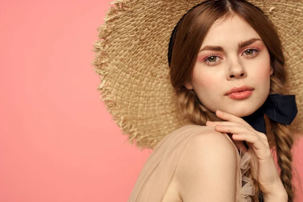 Hasır şapkalı bir kızın portresi pembe arka plan duyguları yakın plan güzel yüz modeli örgüler.