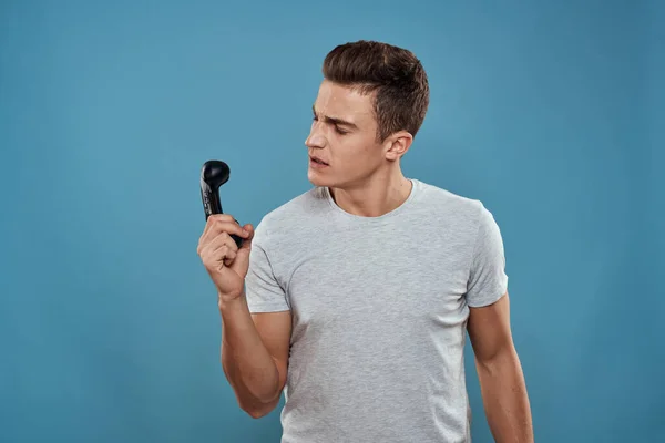 Een man met een joystick in zijn handen entertainment vrijetijdsbesteding technologie video games blauwe achtergrond wit t-shirt — Stockfoto