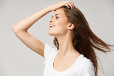 Mutlu kadın beyaz tişört ve eliyle saçlarına dokunuyor. 