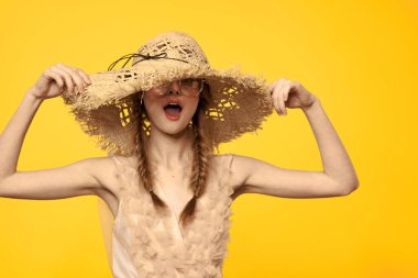 Sarı arka planda saman şapkalı portre kadın. Yazlık elbise mankeni romantizmi.