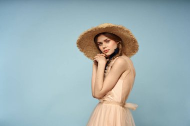 Mavi arka planda pembe elbiseli bir kız elleriyle romantik modeller yapıyor.