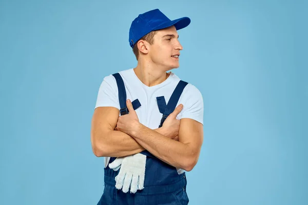 Trabalhador em uniforme de luvas carregador prestando serviço de fundo azul — Fotografia de Stock