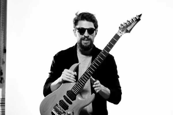 Ein Mann mit einer Gitarre Emotionen Musik Spiel Leistung Lederjacke Sonnenbrille heller Hintergrund — Stockfoto